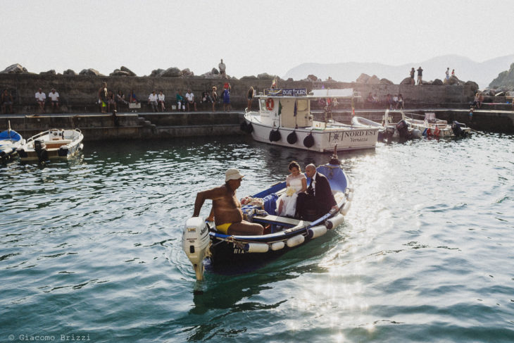 I due sposi in barchetta guidata da un pescatore, fotografo matrimonio Vernazza, Cinque Terre