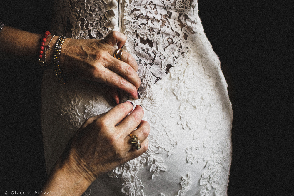 Sistemazione dei dettagli sull'abito della sposa fotografo ricevimento matrimonio valle di badia