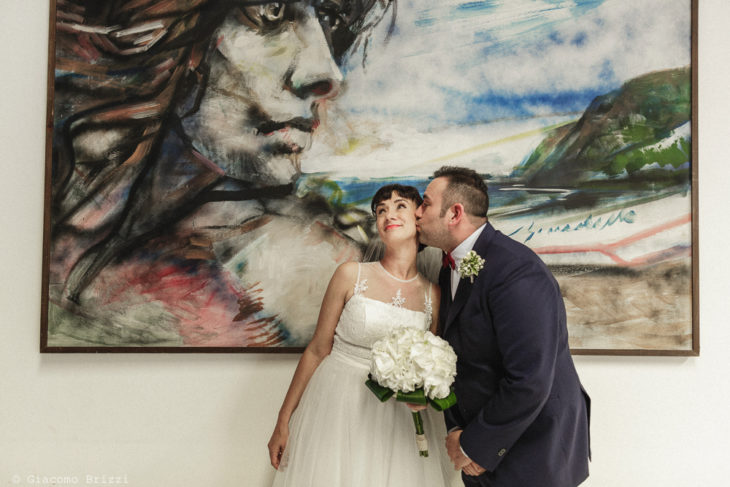 Sposo bacia la sposa con quadro sullo sfondo, matrimonio Massa Carrara Toscana